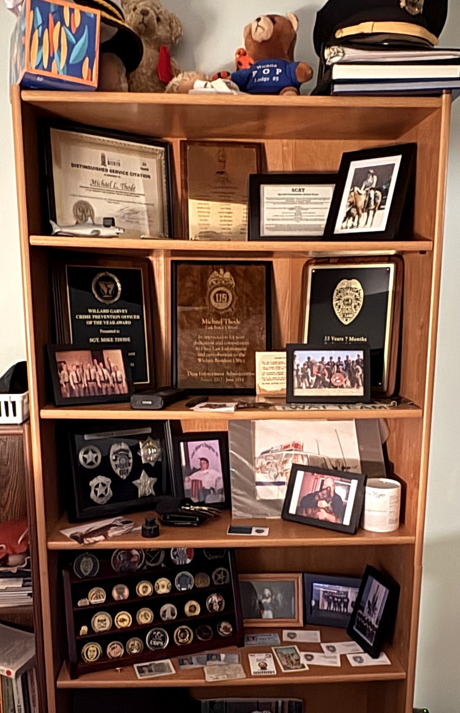 Mike Thode's career memorabilia bookcase: distinguished service citations, plaques, badges, challenge coins and photographs