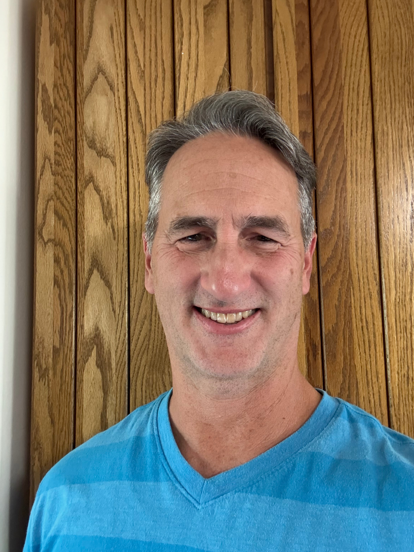Portrait of Mike Thode smiling in front of an oak wall